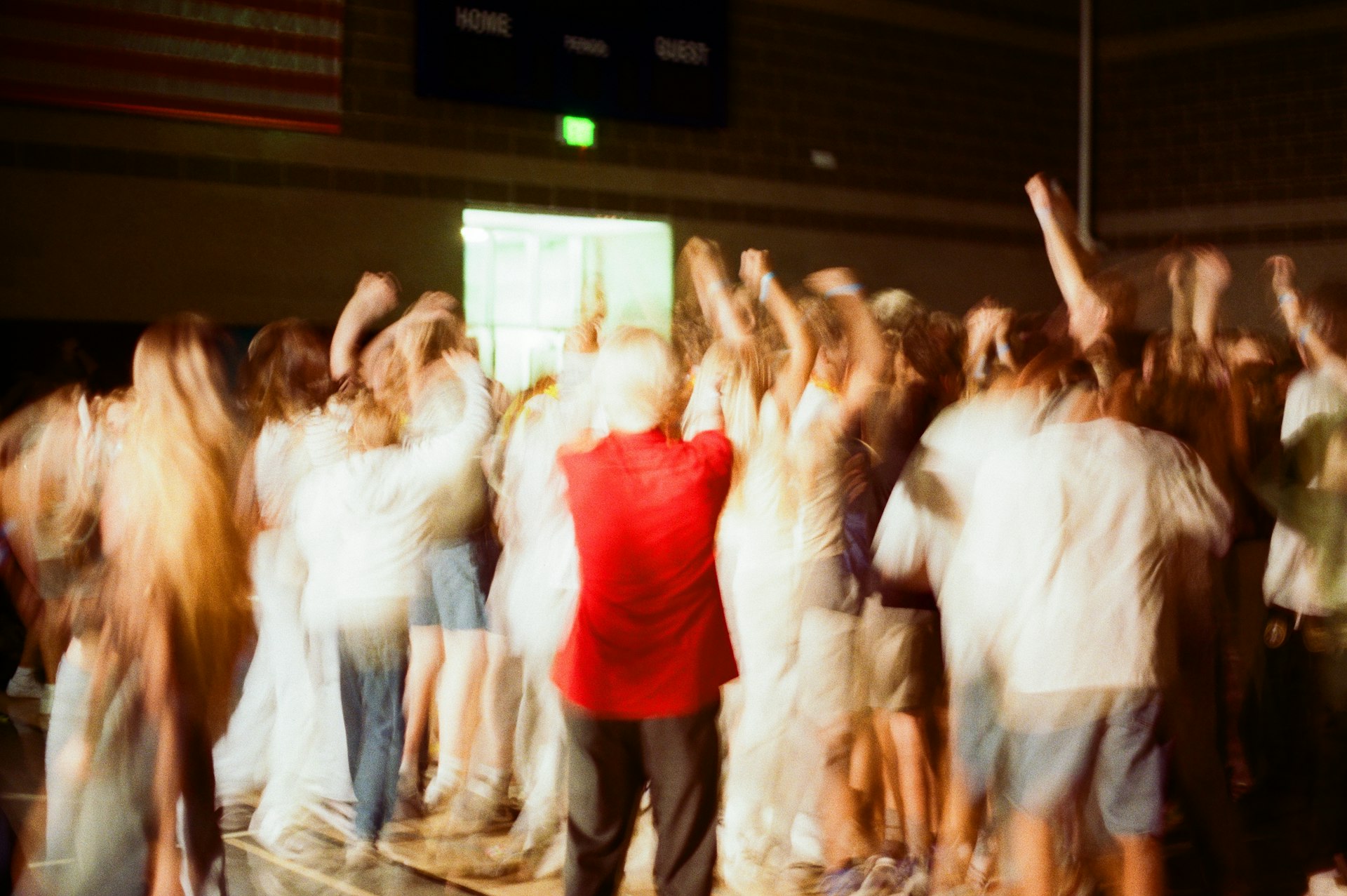 Crowd with arms raised in a gymnasium.